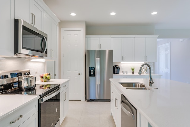 kitchen with light tile patterned flooring, white cabinetry, appliances with stainless steel finishes, backsplash, and sink