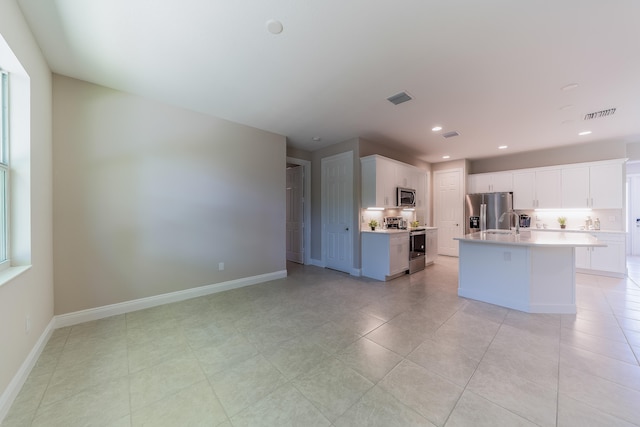 kitchen featuring white cabinetry, appliances with stainless steel finishes, light tile patterned floors, sink, and a kitchen island with sink