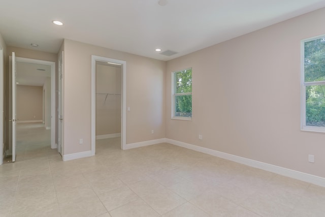 unfurnished bedroom with a spacious closet, light tile patterned floors, and a closet