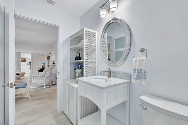 bathroom featuring wood-type flooring, vanity, and toilet