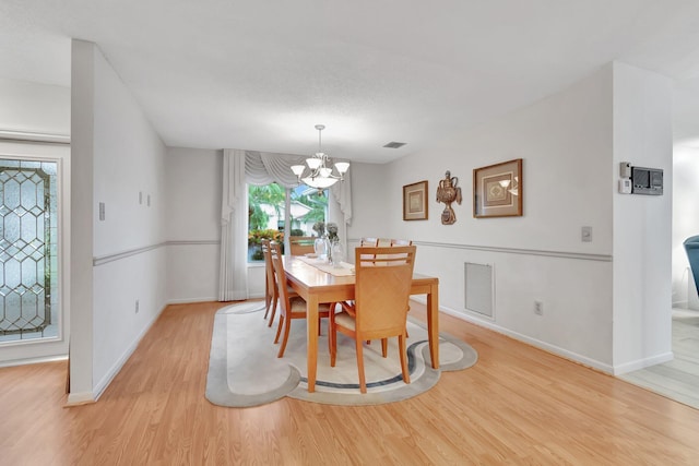 dining space featuring a notable chandelier and light wood-type flooring