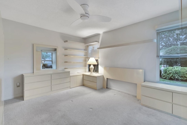 unfurnished bedroom featuring ceiling fan, light carpet, and a textured ceiling