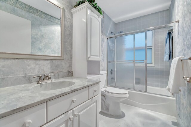 full bathroom featuring vanity, enclosed tub / shower combo, and toilet