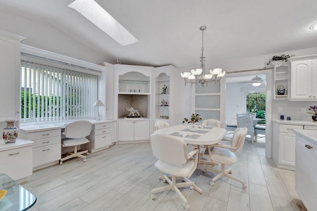 dining room with vaulted ceiling with skylight, light hardwood / wood-style floors, and ceiling fan with notable chandelier