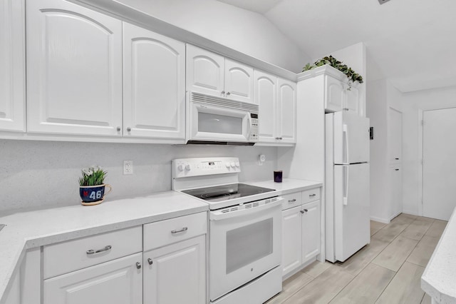 kitchen featuring vaulted ceiling, white cabinets, and white appliances