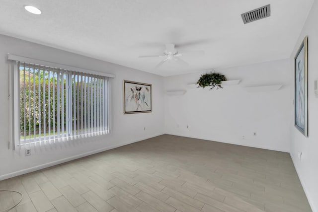 empty room featuring a wealth of natural light, ceiling fan, and light wood-type flooring