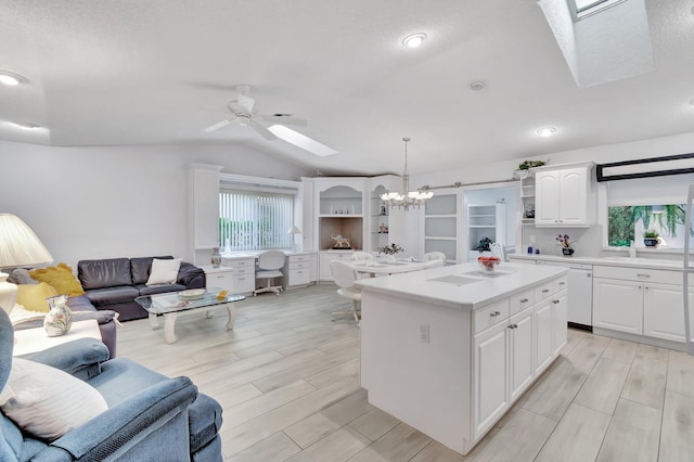 kitchen featuring a center island, decorative light fixtures, lofted ceiling, white cabinets, and ceiling fan with notable chandelier