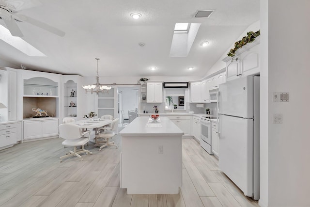 kitchen featuring light wood-type flooring, white appliances, vaulted ceiling, pendant lighting, and white cabinetry