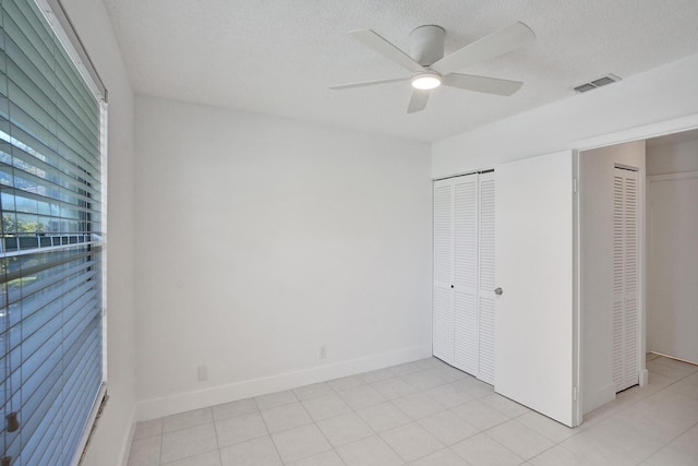 1701 Sabal Ridge Cir Unit G, Palm Beach Gardens, FL 33418 - unfurnished bedroom featuring baseboards, a ceiling fan, a textured ceiling, and two closets
