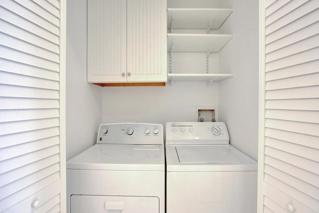 clothes washing area featuring washer and clothes dryer and cabinets