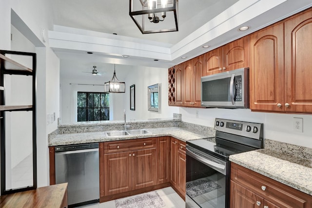 kitchen featuring light stone countertops, ceiling fan with notable chandelier, stainless steel appliances, and sink