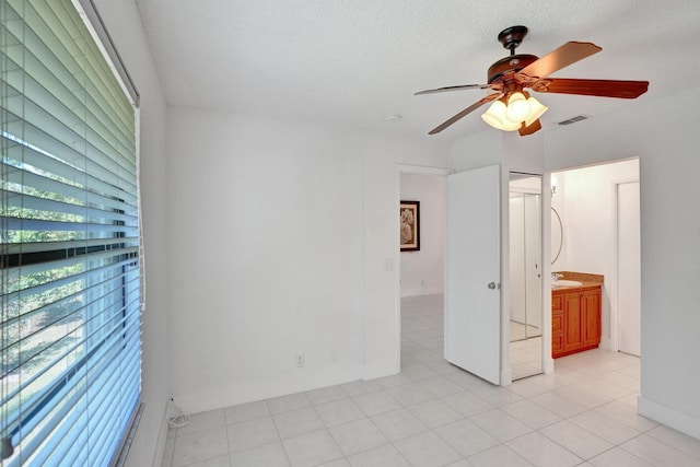 tiled empty room with ceiling fan, sink, and a textured ceiling