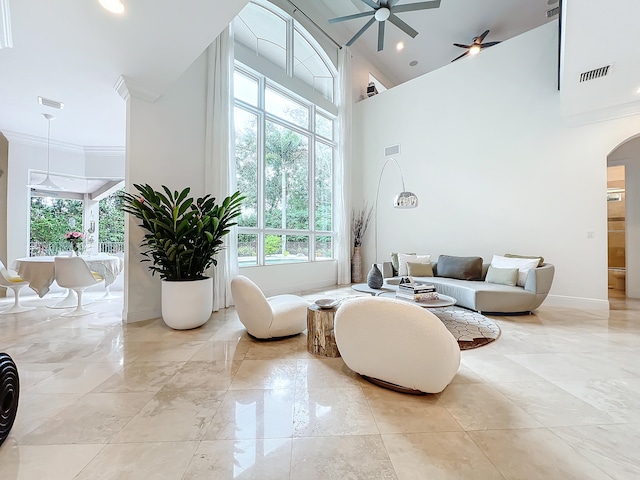 living room featuring ceiling fan, a wealth of natural light, a high ceiling, and crown molding