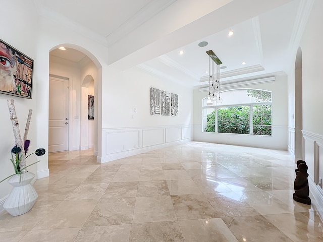 spare room with a tray ceiling, an inviting chandelier, and ornamental molding