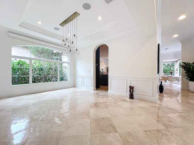 unfurnished room featuring plenty of natural light, a raised ceiling, and ornamental molding