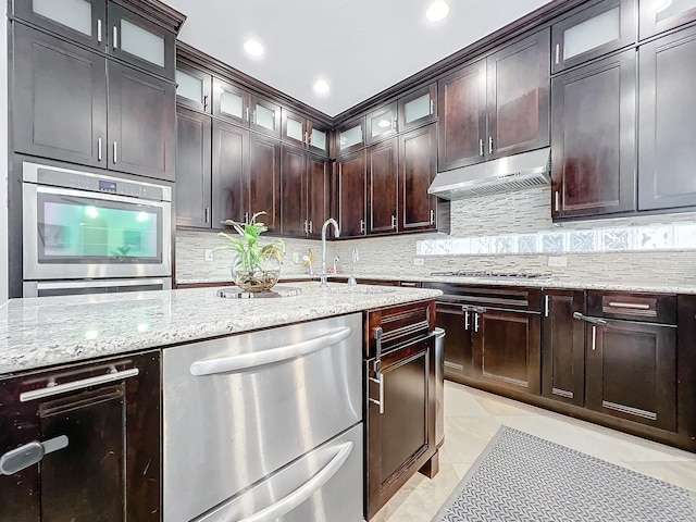 kitchen with stainless steel appliances, light stone countertops, and backsplash