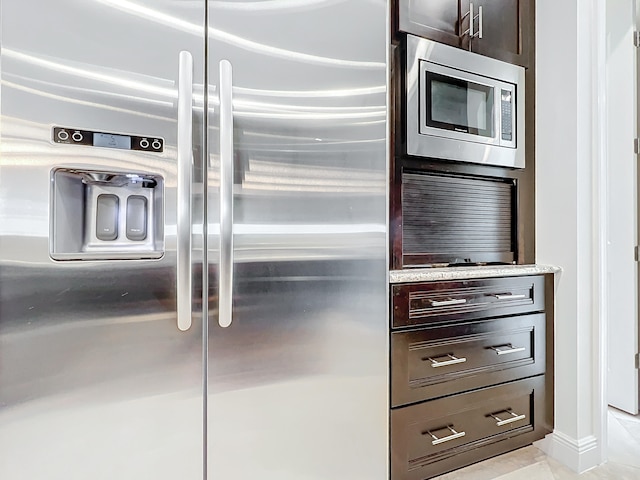 kitchen with dark brown cabinetry, stainless steel appliances, and light tile patterned floors