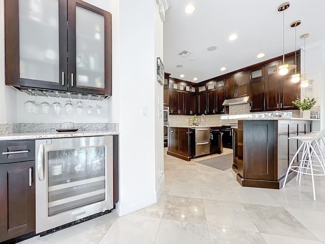 kitchen with wine cooler, a breakfast bar, light stone counters, decorative light fixtures, and dark brown cabinets