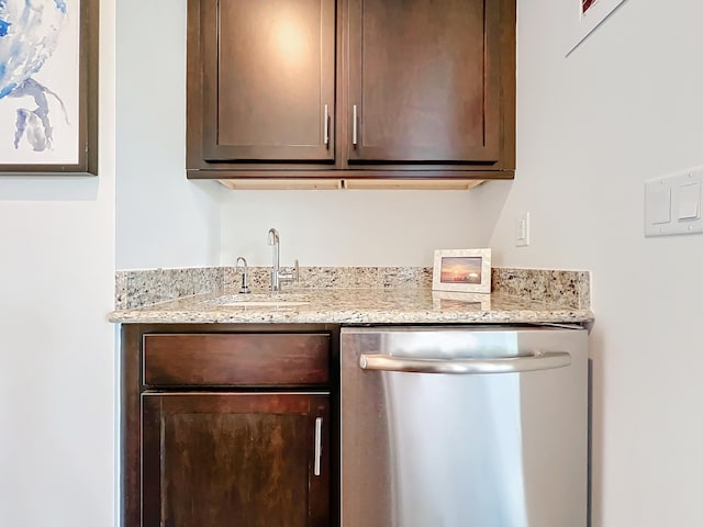 bar with stainless steel dishwasher, dark brown cabinetry, sink, and light stone counters