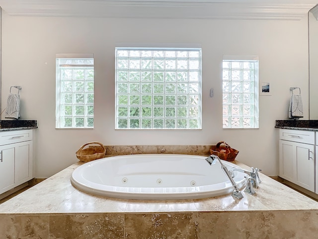 bathroom featuring ornamental molding, vanity, and a relaxing tiled tub