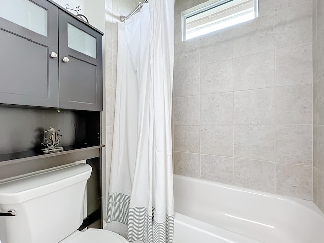 bathroom featuring toilet and shower / bath combination with curtain