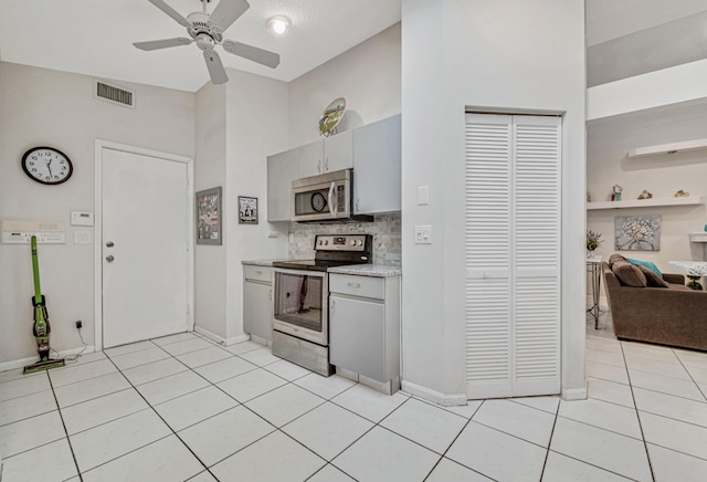 kitchen featuring ceiling fan, gray cabinets, decorative backsplash, light tile patterned floors, and appliances with stainless steel finishes