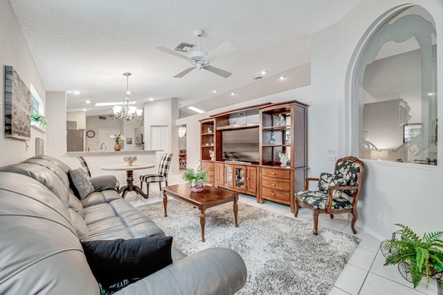 tiled living room with ceiling fan with notable chandelier and a textured ceiling