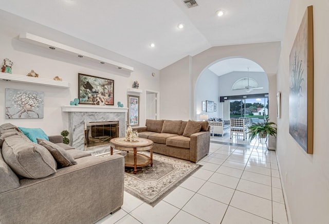 living room featuring ceiling fan, light tile patterned flooring, a high end fireplace, and vaulted ceiling