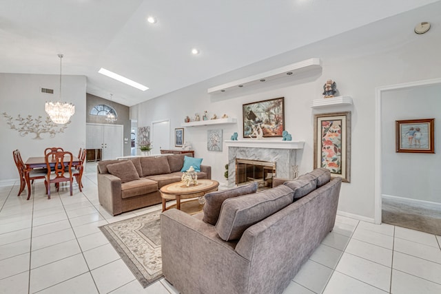 living room featuring lofted ceiling, a fireplace, light tile patterned floors, and an inviting chandelier