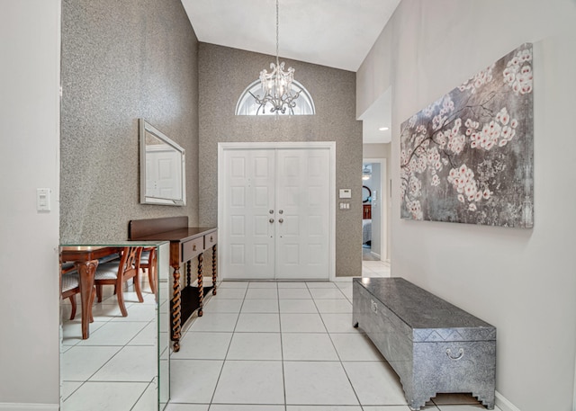 foyer entrance featuring light tile patterned floors, high vaulted ceiling, and a chandelier