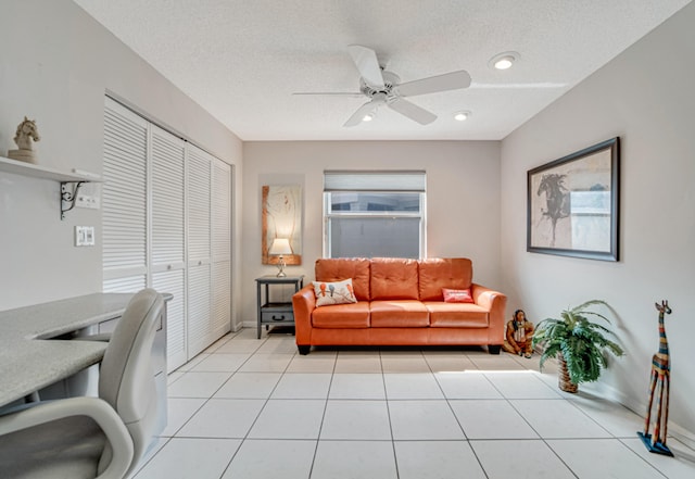 living room featuring ceiling fan, light tile patterned flooring, and a textured ceiling