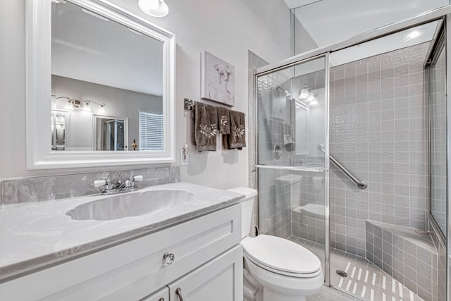 bathroom featuring vanity, toilet, and a shower with door