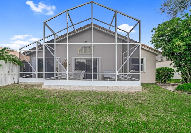 back of property with a lawn and glass enclosure