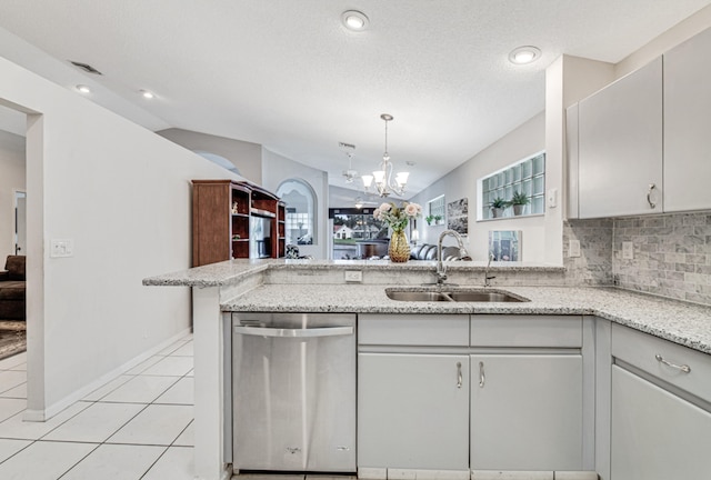 kitchen featuring sink, vaulted ceiling, stainless steel dishwasher, decorative backsplash, and kitchen peninsula