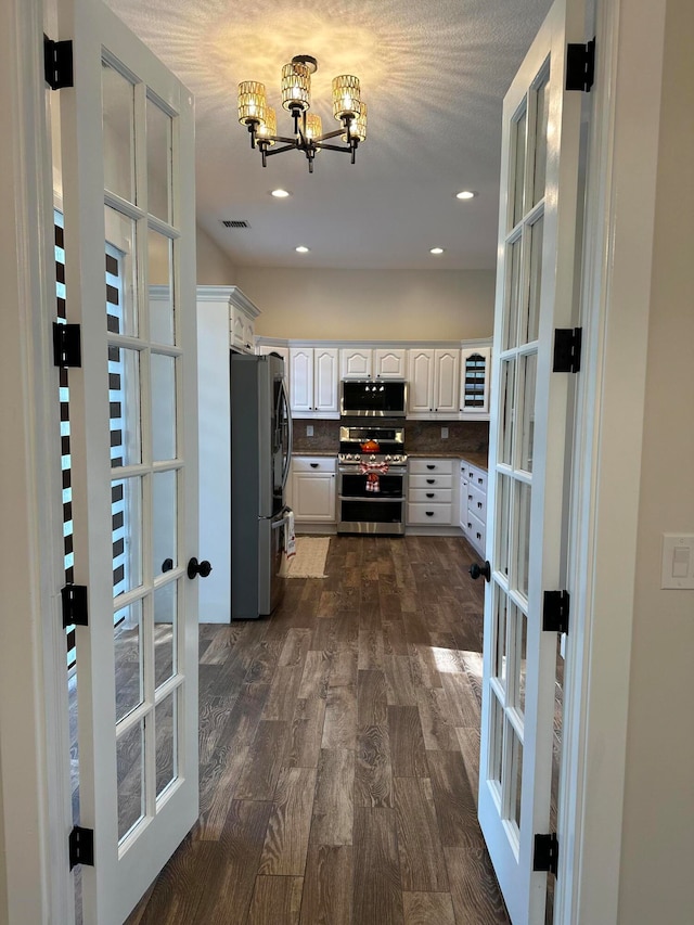 kitchen with dark hardwood / wood-style floors, french doors, white cabinetry, and appliances with stainless steel finishes