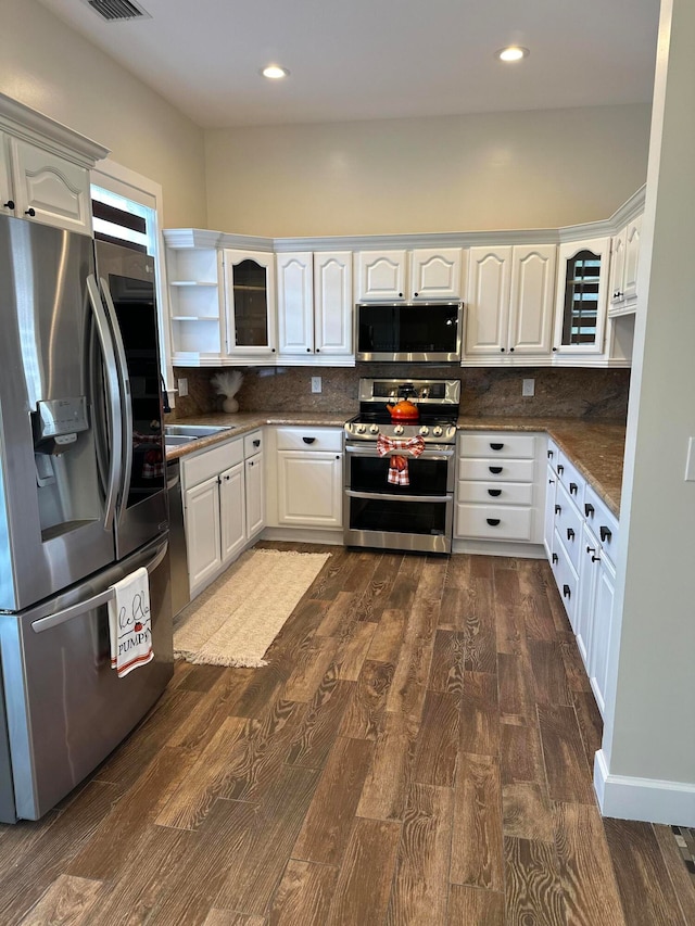 kitchen with dark wood-type flooring, tasteful backsplash, white cabinetry, and appliances with stainless steel finishes