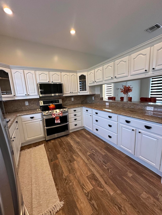 kitchen with dark hardwood / wood-style flooring, white cabinetry, decorative backsplash, and stainless steel appliances