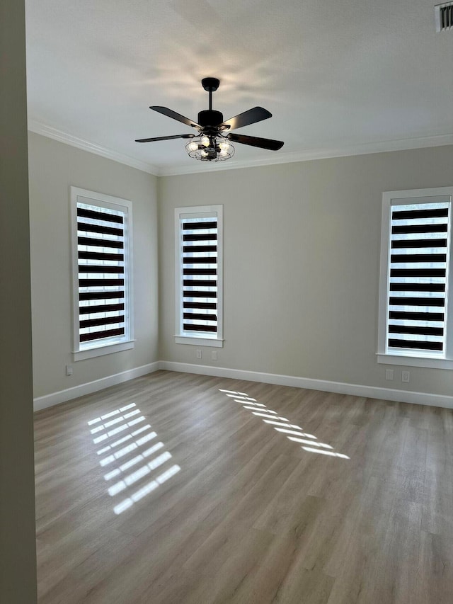 empty room featuring light wood-type flooring, ceiling fan, crown molding, and plenty of natural light