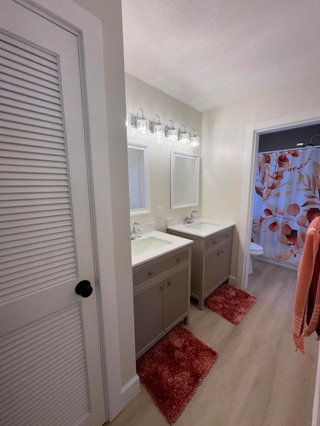 bathroom featuring hardwood / wood-style flooring, vanity, toilet, and a textured ceiling