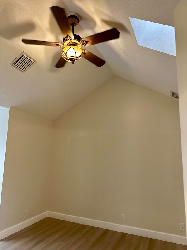 additional living space featuring hardwood / wood-style floors, ceiling fan, and lofted ceiling with skylight