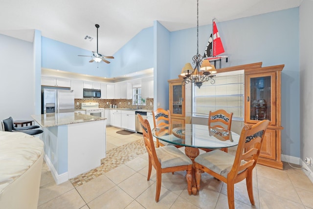 dining area with sink, ceiling fan with notable chandelier, high vaulted ceiling, and light tile patterned flooring