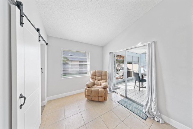 living area with a barn door, light tile patterned flooring, and a wealth of natural light