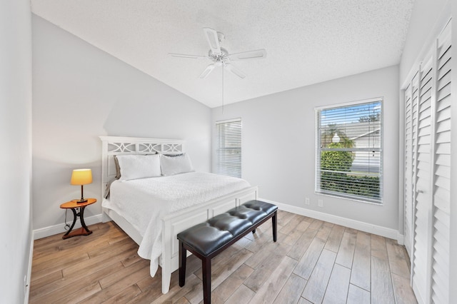 bedroom with ceiling fan, light hardwood / wood-style floors, and a textured ceiling