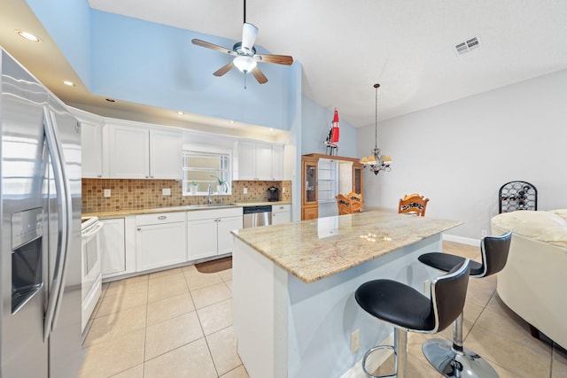 kitchen featuring white cabinetry, a center island, light stone counters, light tile patterned flooring, and appliances with stainless steel finishes