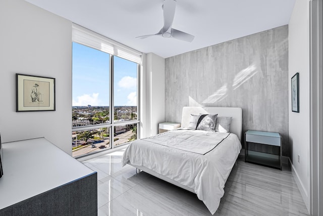 bedroom featuring a wall of windows, baseboards, and a ceiling fan