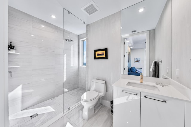 bathroom with a tile shower, vanity, and toilet