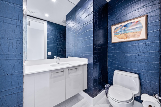 bathroom featuring vanity, tile walls, and toilet