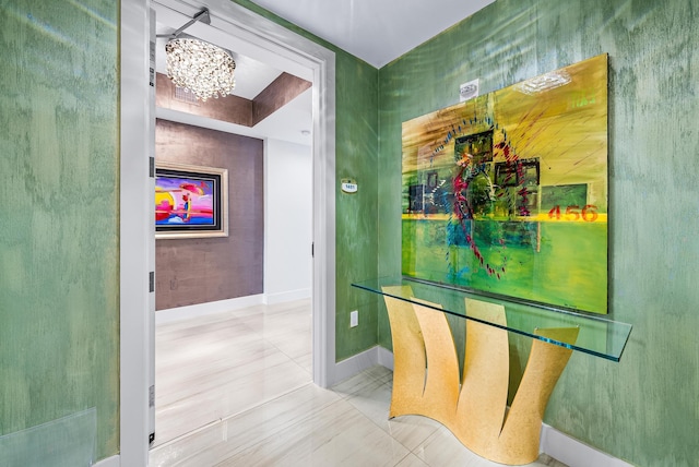 hallway featuring a notable chandelier, tile patterned flooring, and baseboards