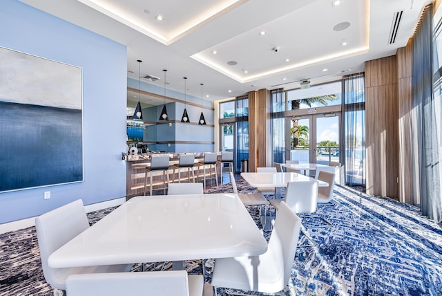 dining space featuring expansive windows, a raised ceiling, french doors, and recessed lighting