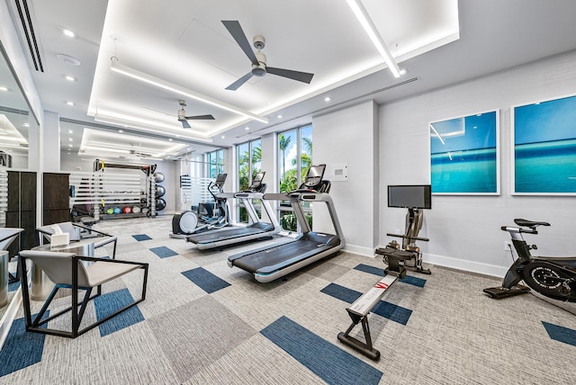 gym featuring baseboards, a ceiling fan, carpet, a tray ceiling, and recessed lighting